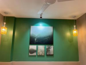a green wall with three pictures on it with lights at Casa Dune in Pune