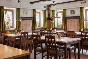 a restaurant with wooden tables and chairs and windows at Gasthaus Alter Wirt in Oberneuching