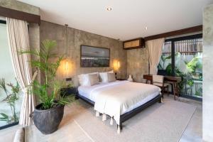 a bedroom with a bed and a potted plant at Atol Villas in Uluwatu