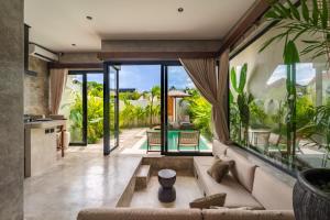 a living room with a couch and a large window at Atol Villas in Uluwatu