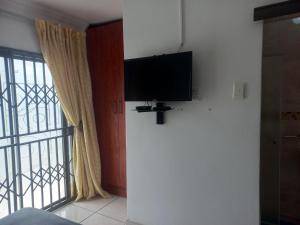 a living room with a flat screen tv next to a window at THE ROSE BnB in Soweto
