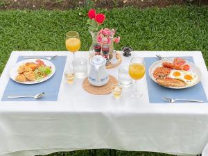a white table with plates of food and glasses of orange juice at F&F Poolvilla Beach Tha Chana in Suratthani