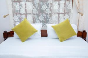 a bed with white sheets and yellow pillows at Arusha Oasis Executive Residence in Arusha