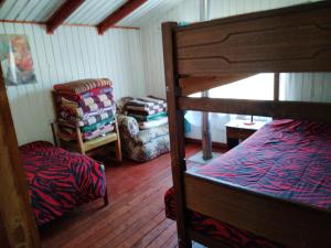 a bedroom with a bunk bed and a chair at Hospedajes y Cabañas Marisol in Curacautín