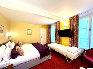 a hotel room with two beds and a large window at Hôtel de Varenne in Paris