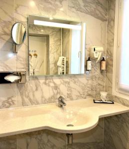 a bathroom with a sink and a mirror at Hôtel de Varenne in Paris +48 photos