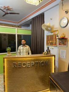 a man is standing behind a reception desk at Hotel Heritage in Varanasi