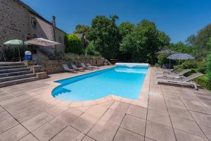 a swimming pool with lounge chairs and umbrellas at La Maison Rouziès in La Bastide-lʼÉvêque