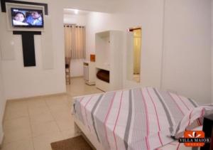 a bedroom with a bed and a tv on a wall at Villa Maior Hotel in São Roque