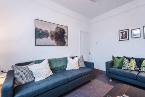 a living room with two blue couches and a table at Spacious 4 Bed Home in Crewe by 53 Degrees Property! Perfect for Groups & Families in Crewe