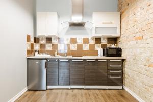 a kitchen with stainless steel appliances and a brick wall at ApartHotel Riga Self Registration & Check-in in Riga