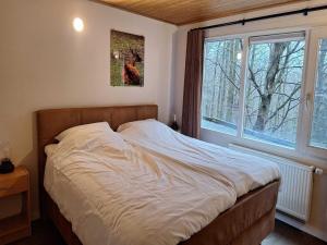 a bed in a bedroom with a large window at Chalet in Manhay for 9 Person in Manhay