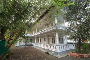 a large white house with a porch and trees at Greenhaven Homestay Villa in Ettumānūr