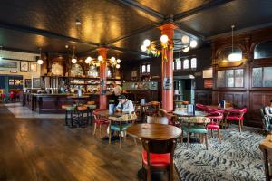 a restaurant with tables and chairs and a bar at The Railway Hotel Worthing in Worthing