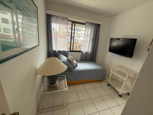 a small bedroom with a bed and a television at Residence Punta del Este 107 in Punta del Este
