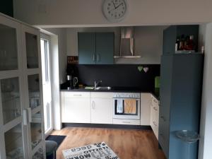 a kitchen with white cabinets and a clock on the wall at FeWo Edelweiß Jäger in Nesselwang