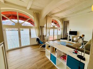 a living room with a couch and a table and some windows at -Ortaflats- Appartamento Gli Archi in Orta San Giulio