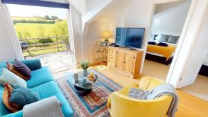 a living room with a blue couch and a television at Georgeham Sweet Pea Cottage in Georgeham