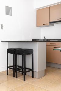 a kitchen with two black stools in front of a counter at Esplanada Studios in Genk