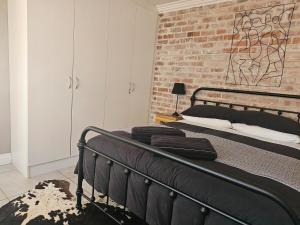 a black bed in a room with a brick wall at Cape Town Glam in Welgemoed