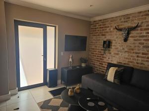 a living room with a couch and a brick wall at Cape Town Glam in Welgemoed