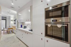 a kitchen with white cabinets and stainless steel appliances at Lavie Maison - Design Suite & Spa Bath in Paris +18 photos