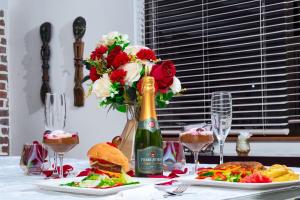 a table with a bottle of champagne and a sandwich and flowers at Nkandla Resort in Bulawayo +9 photos