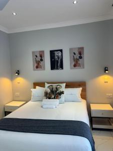a bedroom with a white bed with pictures on the wall at Elephant's Crest Lodge in Victoria Falls +22 photos