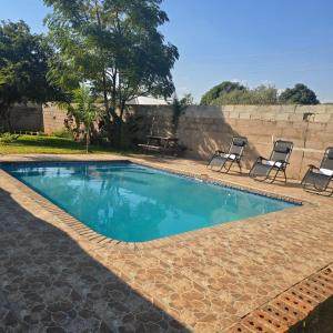 a swimming pool with two chairs and a wall at Elephant's Crest Lodge in Victoria Falls