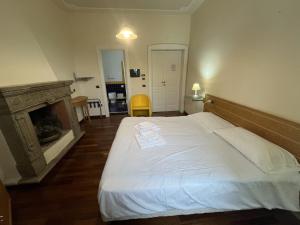 a bedroom with a white bed with a fireplace at Hotel Liberty in Pattada