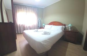 a bedroom with a large white bed with a window at Apartamentos Camino Inglés 3 in O Mesón Do Vento 