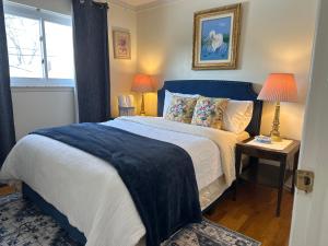 a bedroom with a bed with a blue headboard and two lamps at Charming Getaway Make Memories in Sterling Heights