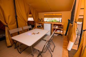 a dining room with a table and chairs in a tent at Camping Onlycamp Les Peupliers in Lepin-le-Lac +18 photos
