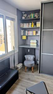 a living room with a chair and a book shelf at Studio cosy à deux pas de Paris in Clichy