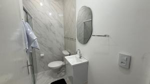 a white bathroom with a sink and a mirror at Flat completo em excelente localização in Chapecó