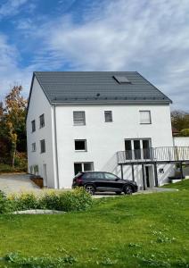 a black car parked in front of a white house at Auszeit im Hegau Bodenseenahe Ferienwohnung in Engen