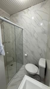 a white bathroom with a toilet and a shower at Flat completo em excelente localização in Chapecó