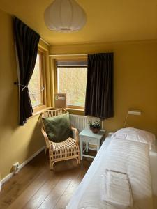 a bedroom with a bed and a chair and a window at Plaats De Kleine Aarde in Boxtel