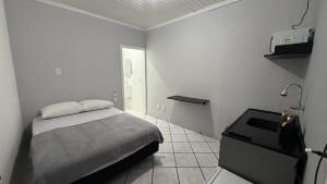 a white room with a bed and a night stand at Flat completo em excelente localização in Chapecó