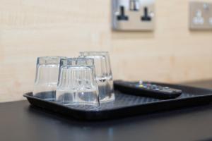 a tray with three glasses and a remote control at St George Hotel Paddington in London