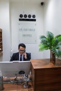 a man sitting at a desk talking on a cell phone at St George Hotel Paddington in London