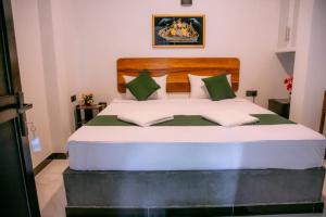 a bedroom with a large bed with green and white pillows at Seaside Serenity Resort in Hiriketiya +12 photos