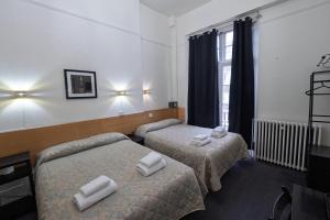 a hotel room with two beds with white towels on them at St George Hotel Paddington in London +141 photos