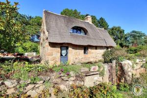 an old stone house with a thatched roof at La chaumière in Pleumeur-Bodou