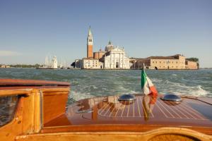 a boat on the water with a flag on it at Gabrielli Luxury Apartments Venezia - Starhotels Collezione in Venice