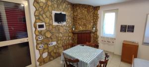 a dining room with a table and a tv on a stone wall at casa vacanza Teresa 2 in Vieste