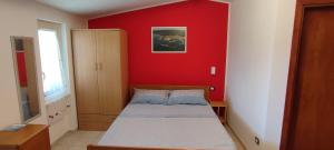 a small bedroom with a bed and a red wall at casa vacanza Teresa 2 in Vieste