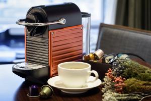 a cup of coffee sitting on a table with a coffee machine at Aguila Hotel Jeju Oceano Suite in Jeju