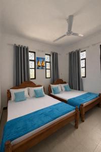 two beds sitting in a room with windows at Ebruli Guest House in Nungwi
