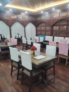 a dining room with tables and white chairs at White blossom in Srinagar